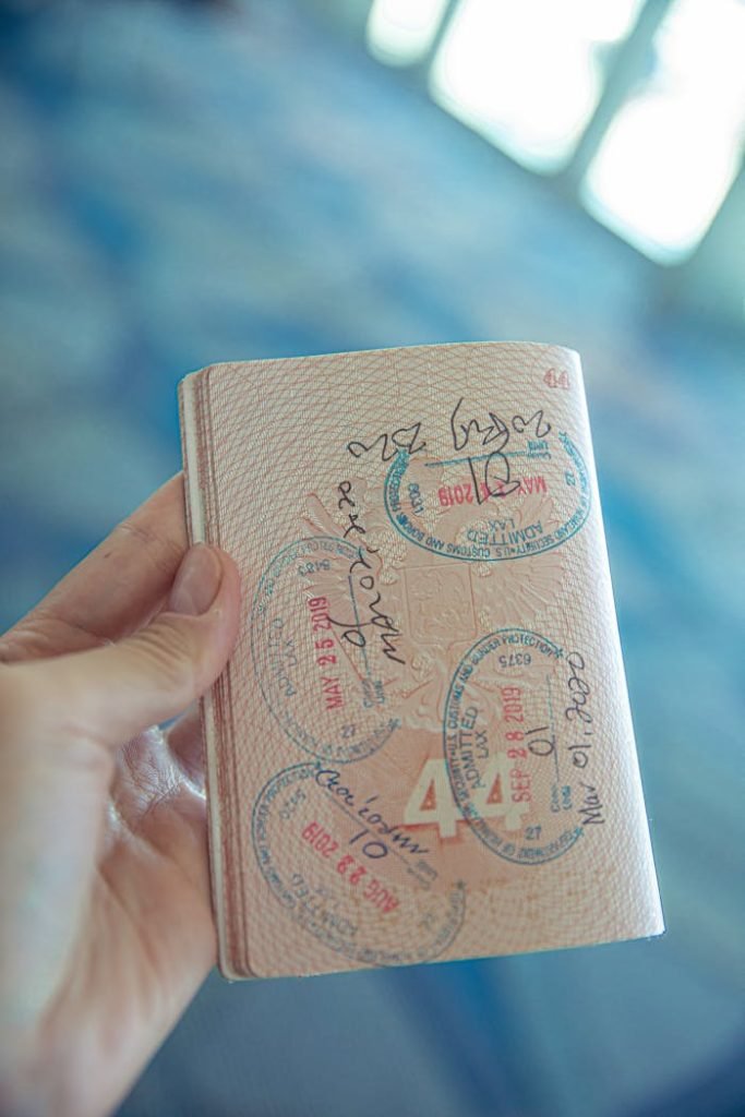 A close-up view of a hand holding an open passport with various stamps, highlighting travel experiences.