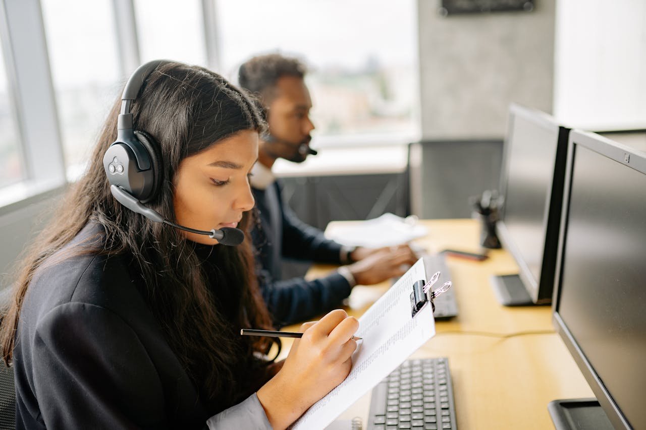 woman with headset holding a clipboard and taking notes 8867429